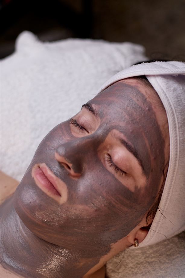 Clienta relajada con mascarilla de arcilla durante un facial