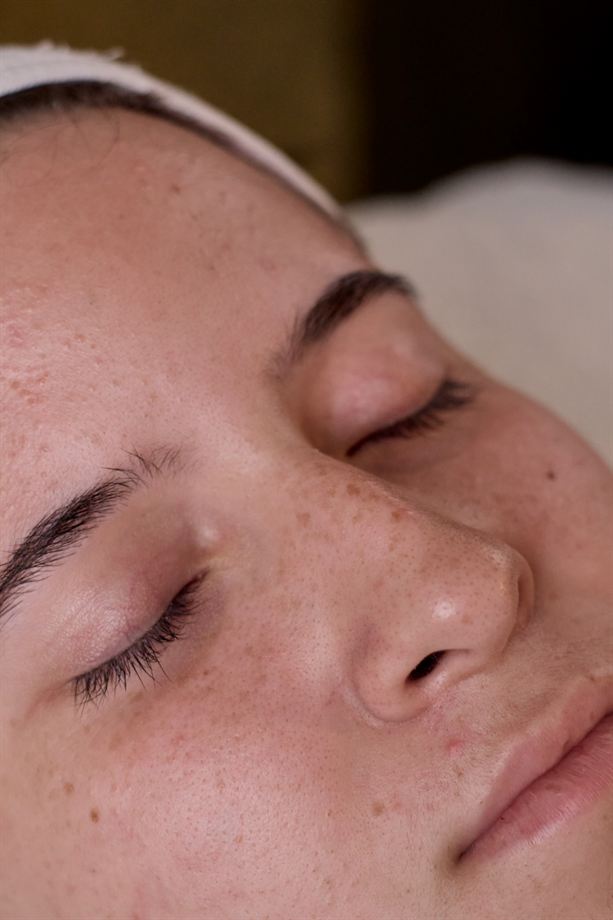 Primer plano de la piel de una clienta con los ojos cerrados durante un facial